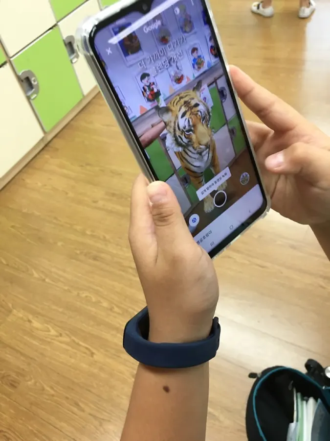 휴대폰 화면에 증강현실 호랑이가 나타난 모습