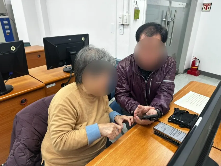 강사가 어르신 옆에서 휴대폰 사용을 돕는 모습